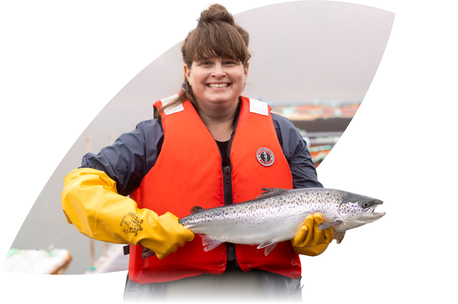 Woman in a life vest holding up an atlantic salmon